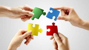 Hands and puzzle on gray background. Teamwork solving a puzzle